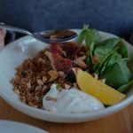 A vibrant brunch bowl with fruit, greens, and nuts for a nutritious meal.